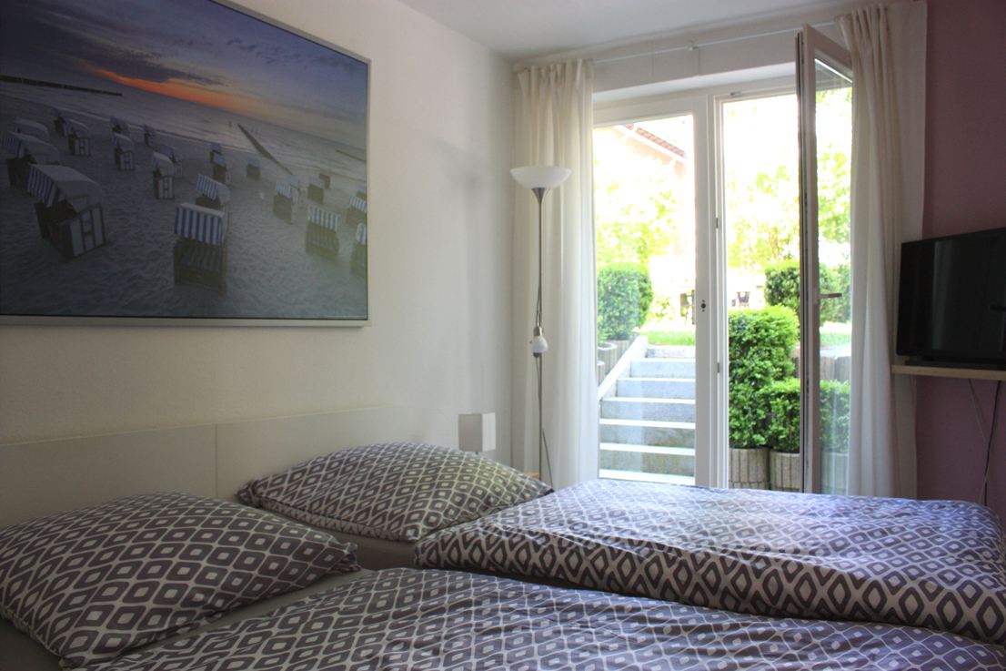 Schlafzimmer mit zwei Einzelbetten und Glastür zum Garten